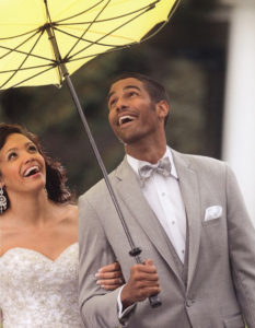 Happy wedding couple under yellow umbrella.