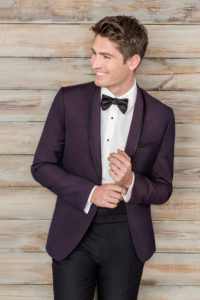 Smiling man in purple tuxedo and bow tie.