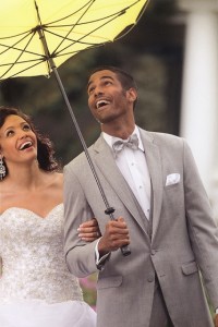 Happy bride and groom under yellow umbrella