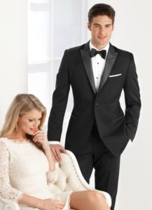Man in tuxedo with woman in lace dress.