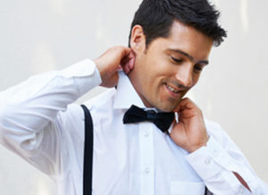 Man adjusting his bow tie and suspenders.