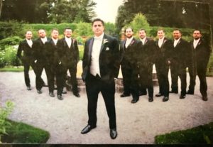 Groom posing with his groomsmen in tuxedos.