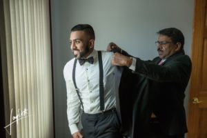 Father helps groom put on his jacket.