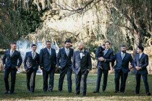 Groom and groomsmen pose outdoors.