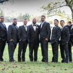 Groomsmen and child in suits outdoors.