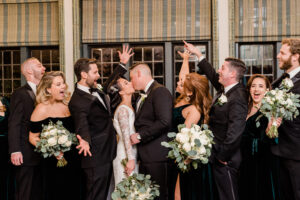 Bride and groom kissing, wedding party cheering.