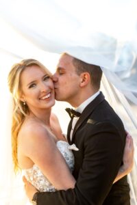 Bride and groom kissing under veil.
