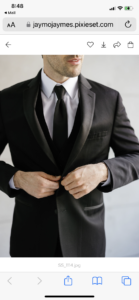 Man in black tuxedo adjusting jacket.