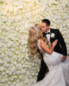 Bride and groom kissing, floral backdrop.
